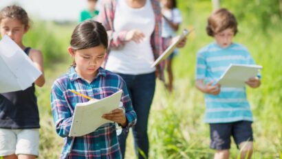Children and guide taking notes while exploring outside.