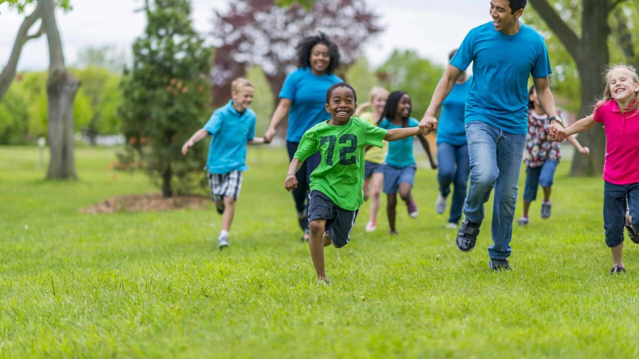 Children and adults running a race and holding hands.