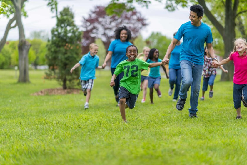 Children and adults running a race and holding hands.